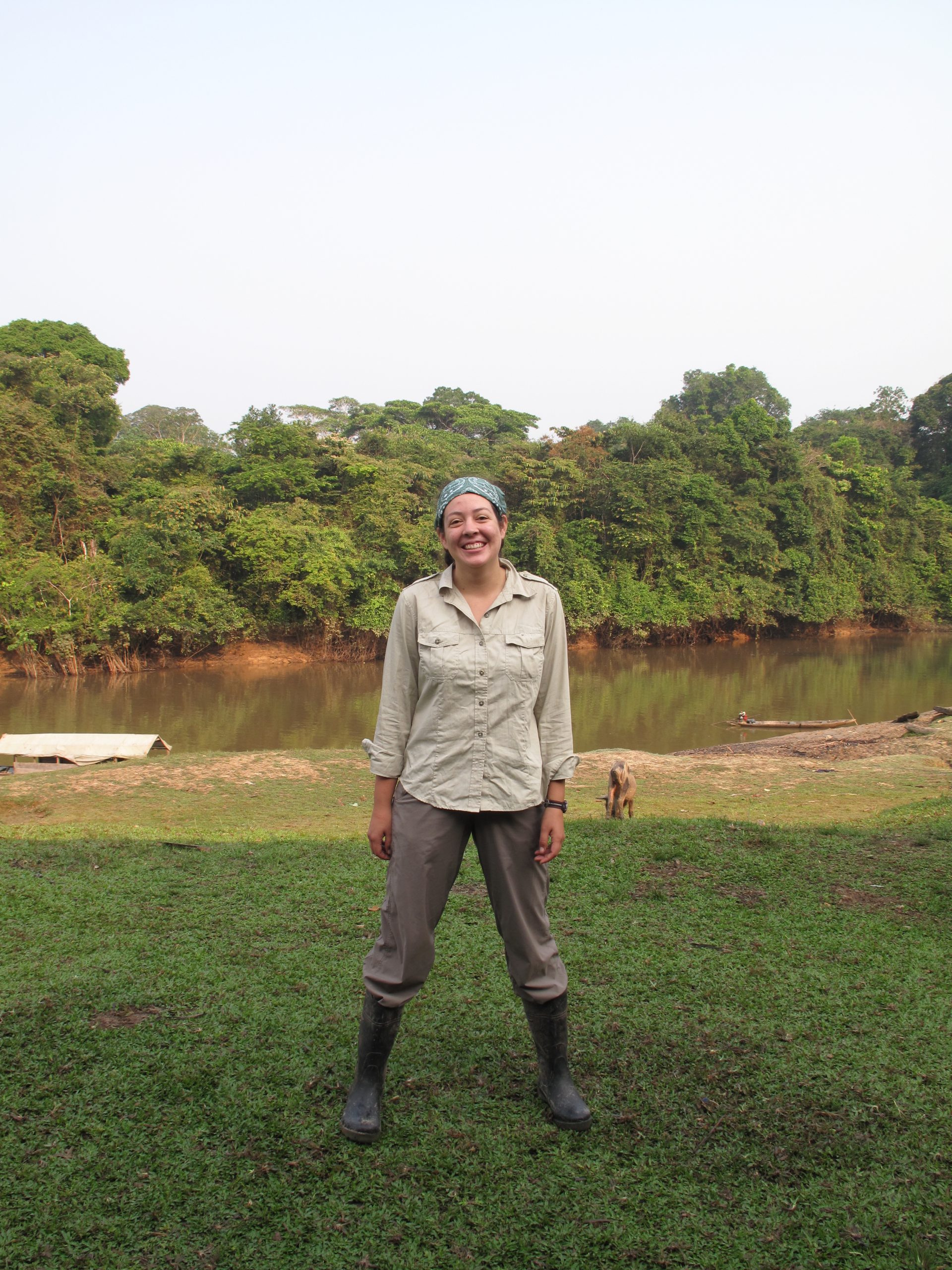 A woman in rubber boots standing before a river in the Amazon Basin