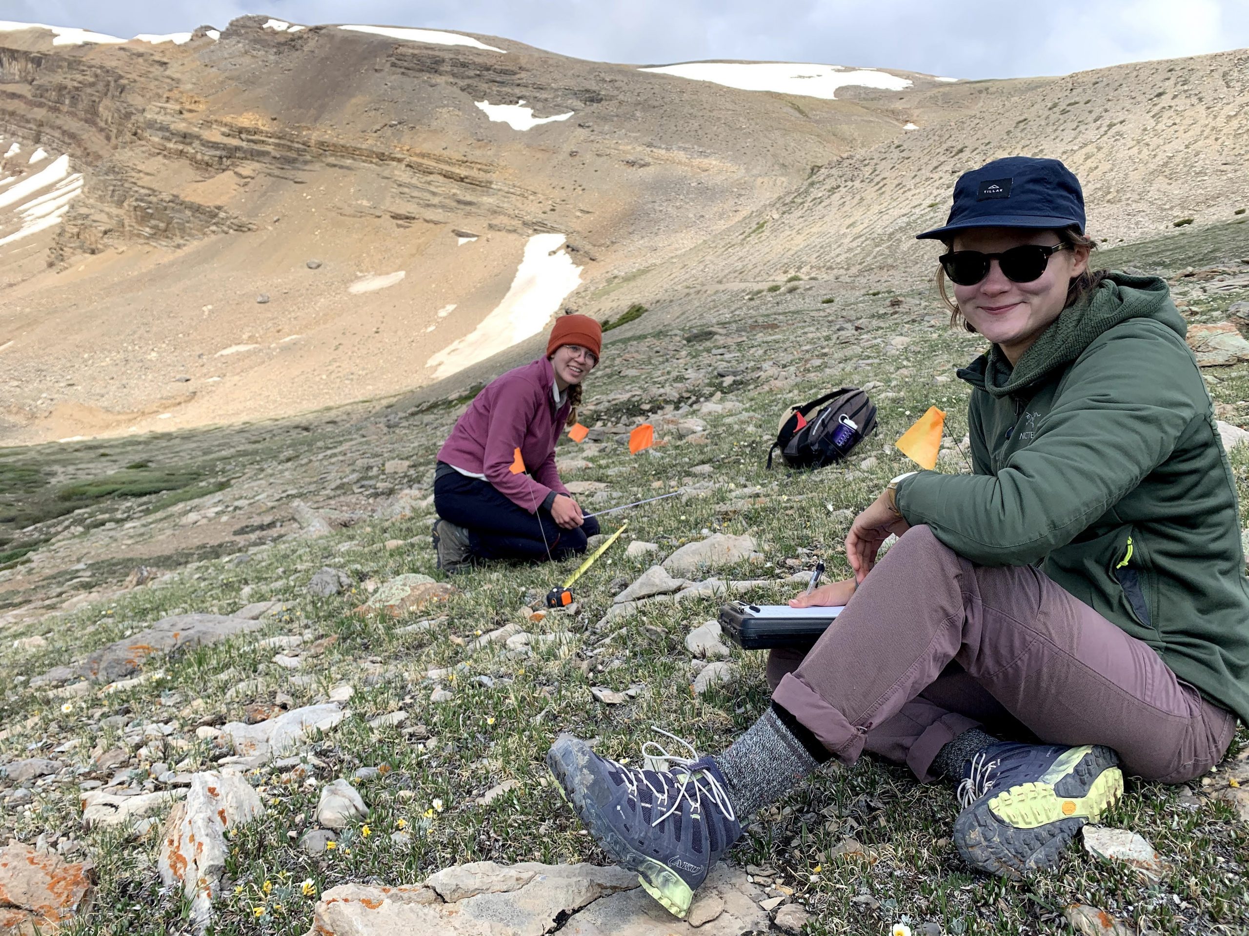 Two women sitting in Colorado alpine habitat.
