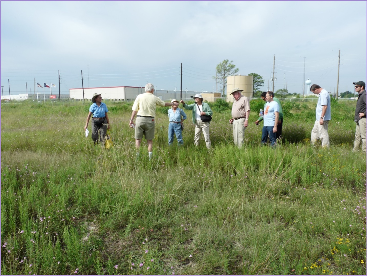 A group of people standing in prairie grasses.