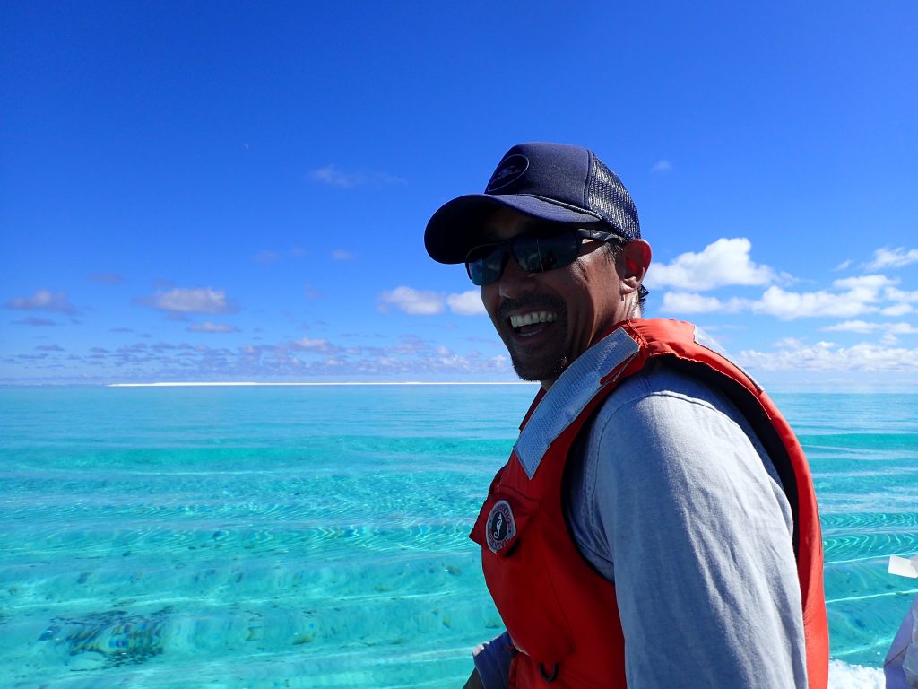 Photo of James Kwon in safety vest and hat with clear ocean water and sand bar in background.